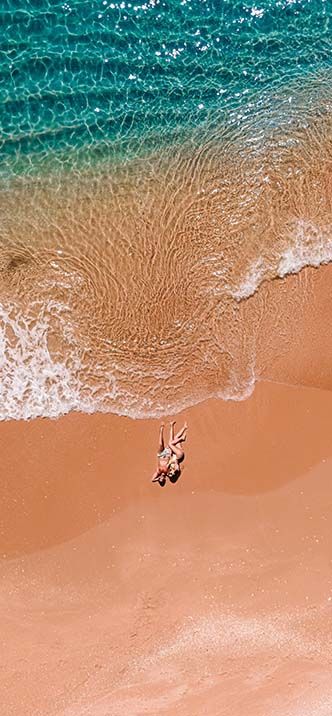 Top-down view of clear waves on Carvoeiro sandy beach.