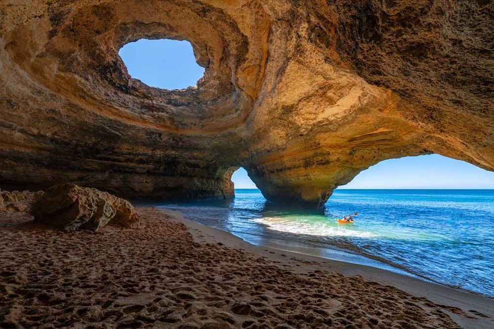 Carvoeiro beach cave with natural arch and kayaker.