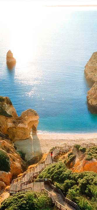 Cliffside stairs to Carvoeiro beach, sea view at sunrise.