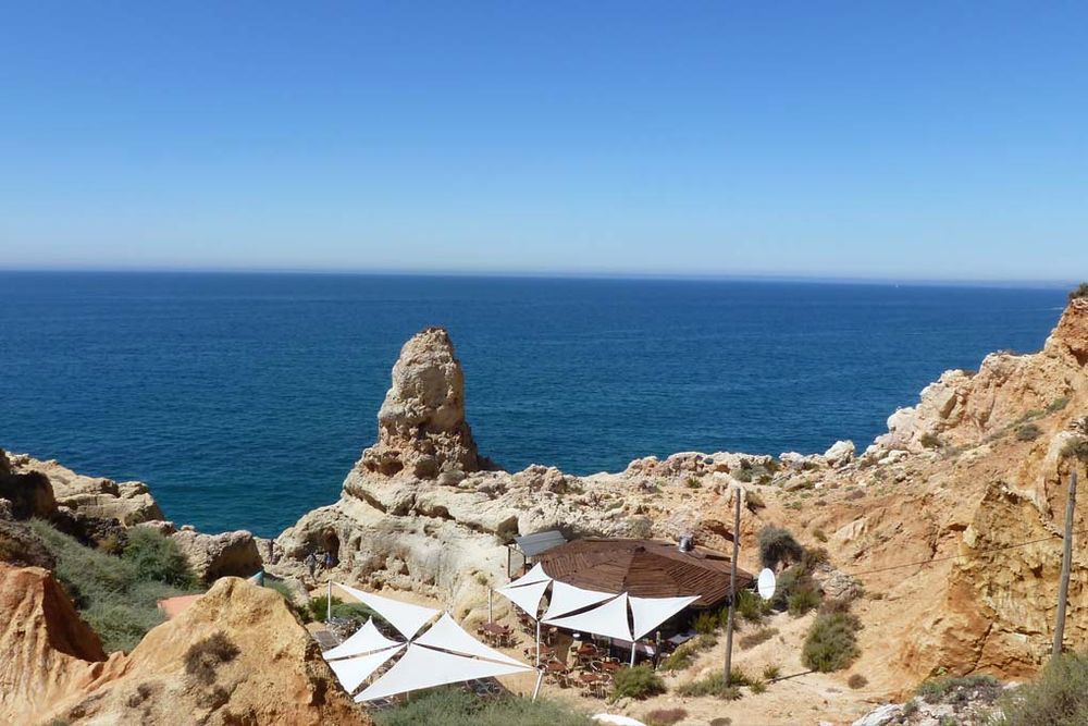 Seaside view in Carvoeiro with rocky cliffs and a coastal café.